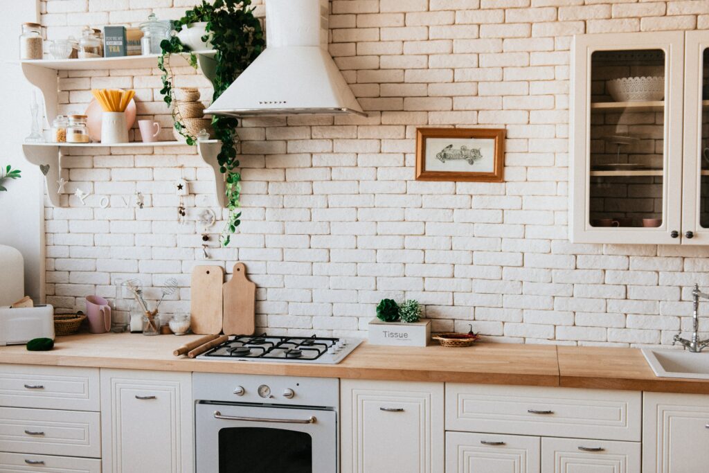 A light kitchen interior with cream cupboards, drawers, and walls, and a natural wood counter.